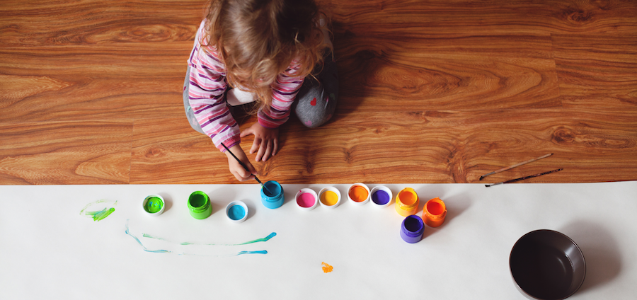 A young girl paints on the floor.