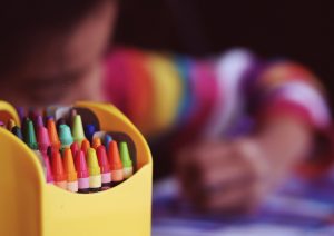 Picture of a child coloring with crayons.
